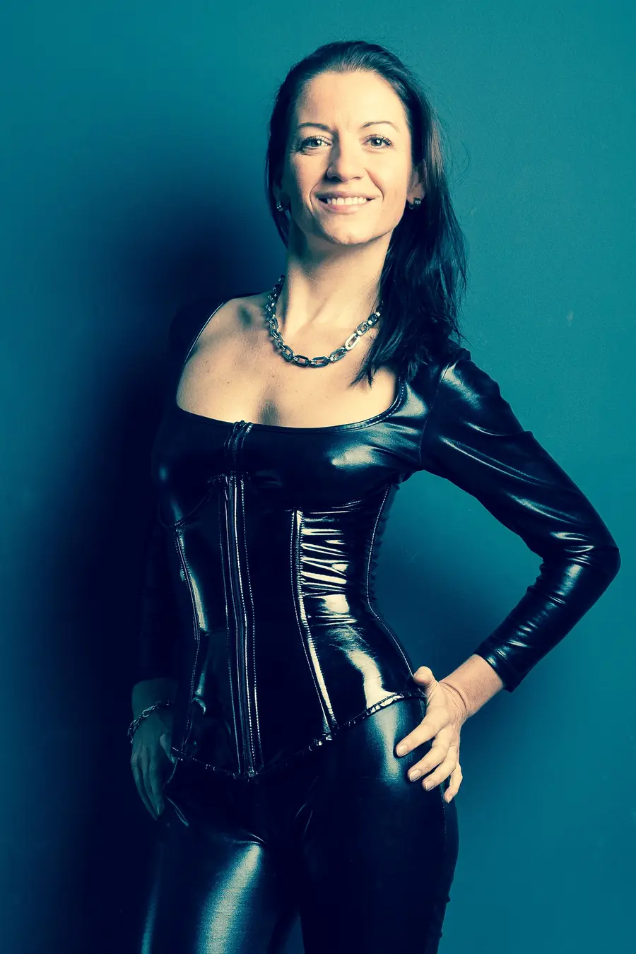 Illustrative stock portrait of a confident woman wearing black against a teal background