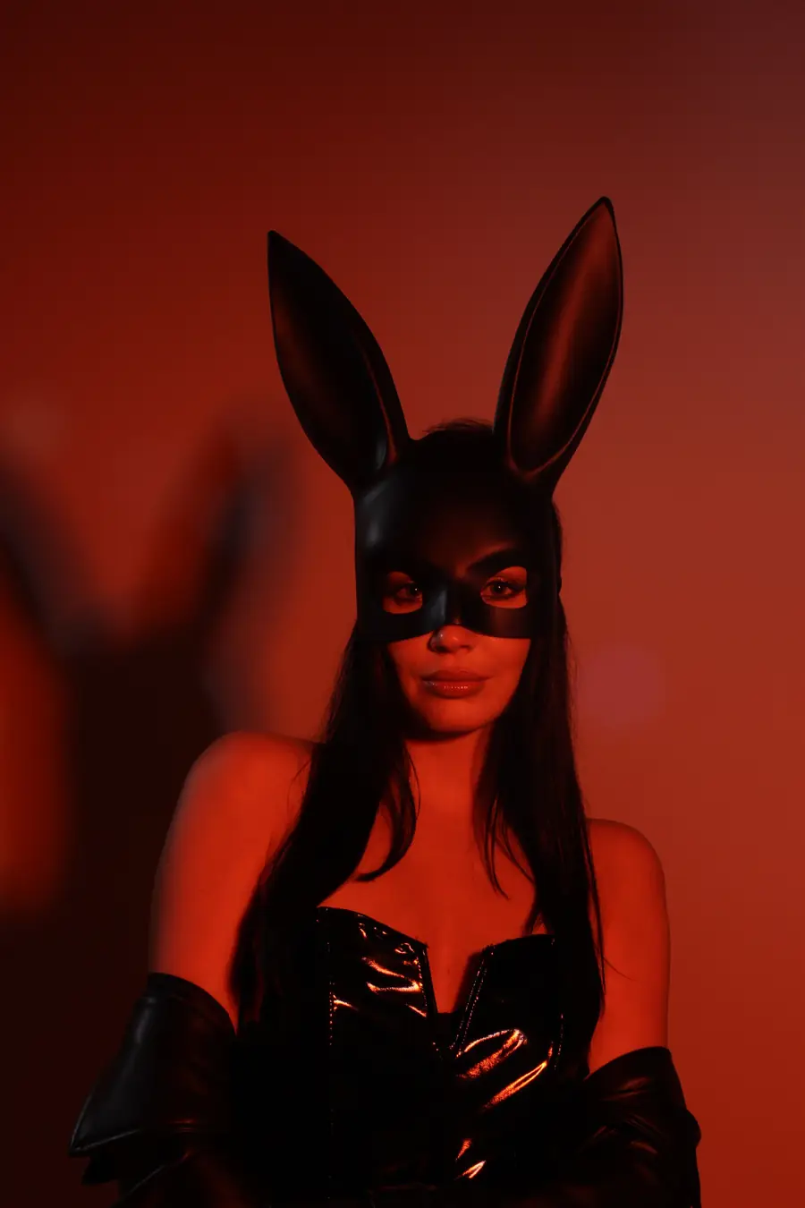 Illustrative stock portrait of a masked woman in a dark red setting